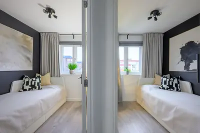 two beds in a room with two windows at ComfySleep ApartHOUSE in Glasgow