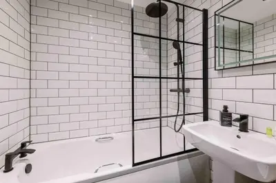 a bathroom with a tub and a sink and a shower at ComfySleep ApartHOUSE in Glasgow