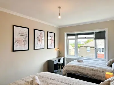 a bedroom with two beds and a window at 4 Bedrooms Homely House - Sleeps 6 Comfortably with 6 Double Beds,Glasgow, Free Street Parking, Business Travellers, Contractors, & Holiday-Goers, Near All Major Transport Links in Glasgow & City Centre, Perfect for Common Wealth Games 2026 in Glasgow