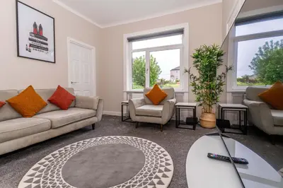 a living room with two couches and a table at 4 Bedrooms Homely House - Sleeps 6 Comfortably with 6 Double Beds,Glasgow, Free Street Parking, Business Travellers, Contractors, & Holiday-Goers, Near All Major Transport Links in Glasgow & City Centre, Perfect for Common Wealth Games 2026 in Glasgow