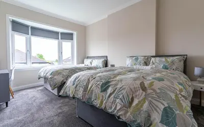a bedroom with two beds and a window at 4 Bedrooms Homely House - Sleeps 6 Comfortably with 6 Double Beds,Glasgow, Free Street Parking, Business Travellers, Contractors, & Holiday-Goers, Near All Major Transport Links in Glasgow & City Centre, Perfect for Common Wealth Games 2026 in Glasgow