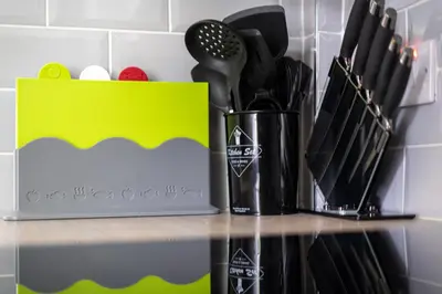 a counter with a knife block and a yellow box at 4 Bedrooms Homely House - Sleeps 6 Comfortably with 6 Double Beds,Glasgow, Free Street Parking, Business Travellers, Contractors, & Holiday-Goers, Near All Major Transport Links in Glasgow & City Centre, Perfect for Common Wealth Games 2026 in Glasgow