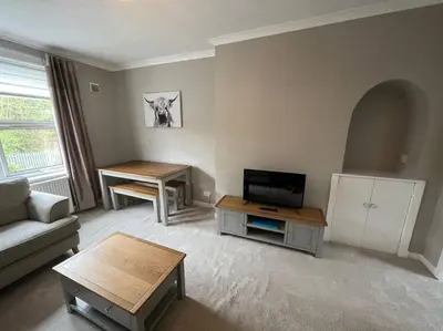 a living room with a couch and a tv and a table at Cosy Cottage Apartment in Helensburgh