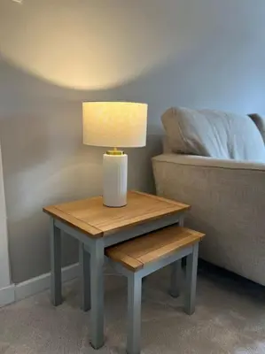 a table with a lamp on it next to a bed at Cosy Cottage Apartment in Helensburgh