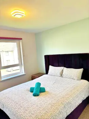 a blue stuffed animal is sitting on a bed at 3 bed house with parking near airport in Edinburgh