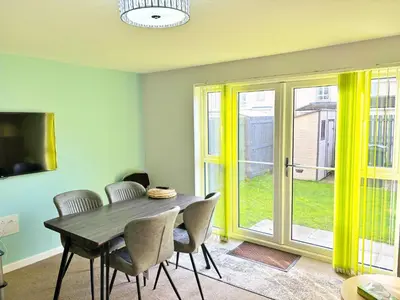 a dining room with a table and chairs and a sliding glass door at 3 bed house with parking near airport in Edinburgh