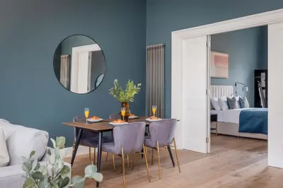 a dining room with a table and chairs and a mirror at Dragon Suites Luxury Serviced Apartments at Walker Street in Edinburgh